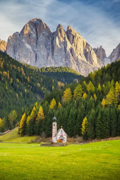 Beautiful view of historic Church of St. Johann of Nepomuk with famous Odle Group mountain peaks in the Dolomites in beautiful evening light at sunset, South Tyrol, Italy