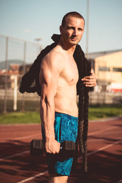 istock Athlete with a weight and a battle rope 958112932