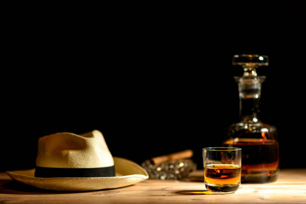Elegant tray with two glasses of rum, cuban cigars, chocolate and coffee beans. The tray is adorned with tobacco leaves. 