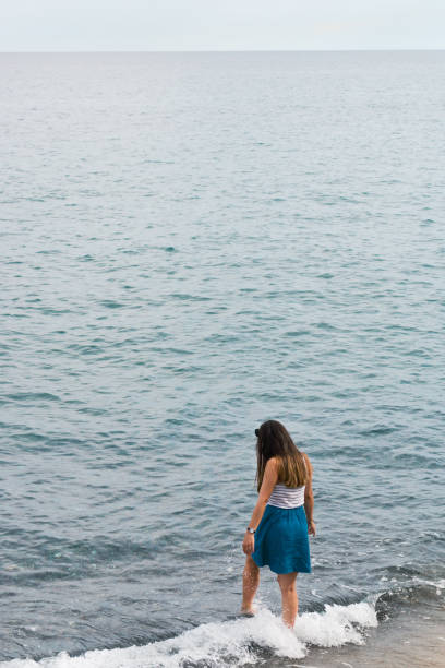 istock Girl walking into sea Italy 958115190