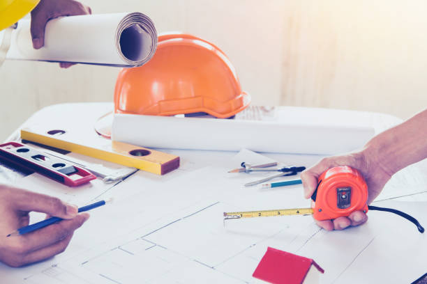istock Concept architects,engineer holding pen pointing equipment architects On the desk with a blueprint in the office, Vintage, Sunset light.Selective Focus 958118778