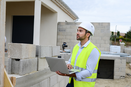 handsome young man foreman architect supervising a new house construction site