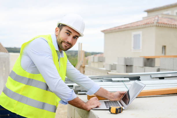 Middle-aged male construction technician wearing work helmet and protective workwear, working at a construction site