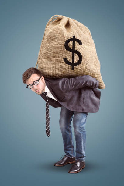 istock Businessman carrying an oversized moneybag 958125856