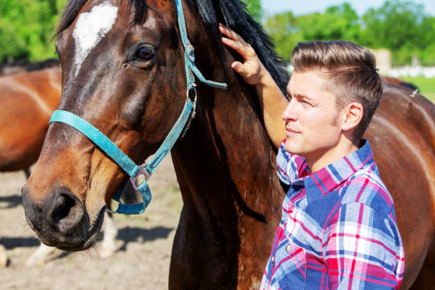 istock handsome blond man with brown horse outdoors 958126230