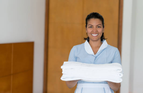 istock Friendly chambermaid holding towels for hotel guests looking at camera smiling 958126582