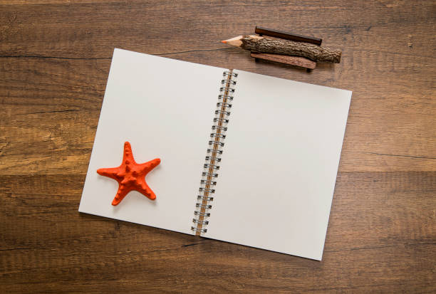 istock Blank white open notebook with orange starfish and color pencil on table 958129668