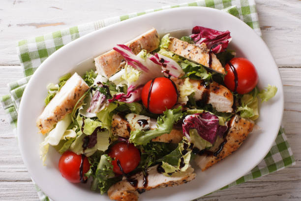 istock Sliced grilled chicken with mixed salad and tomatoes close-up. Horizontal top view 958135344
