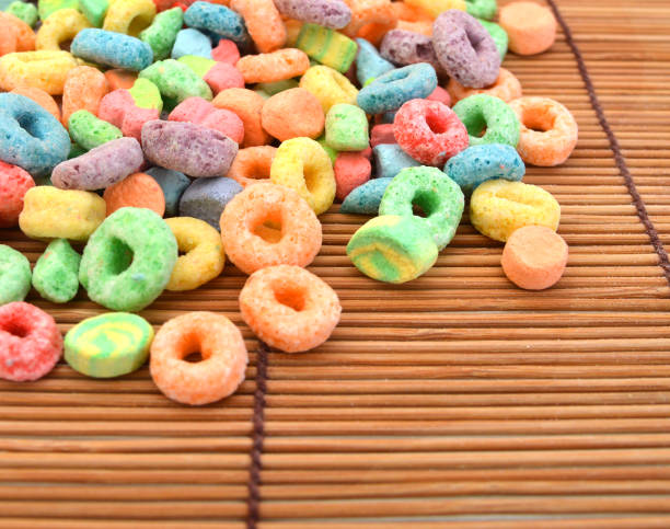 Delicious and nutritious fruit cereal loops flavorful on white background, healthy and funny addition to kids breakfast on bamboo mat