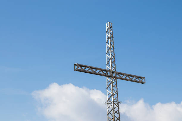 istock Mountain cross in a beautiful blue sky and clouds composition 958150270