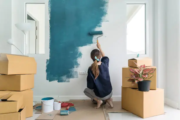 Photo of Young asian happy woman painting interior wall