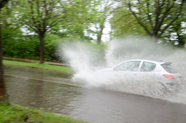 Sonderborg, Denmark - May 10, 2018:  A car splashes trough water on a road that is flooded afther a heavy rainfall. .