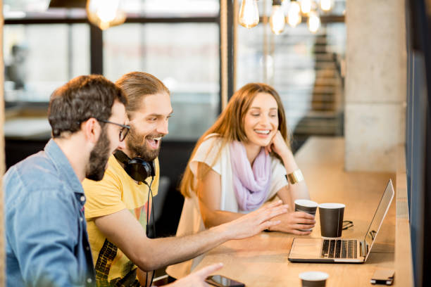 istock Happy colleagues with laptop in the cafe 958157548