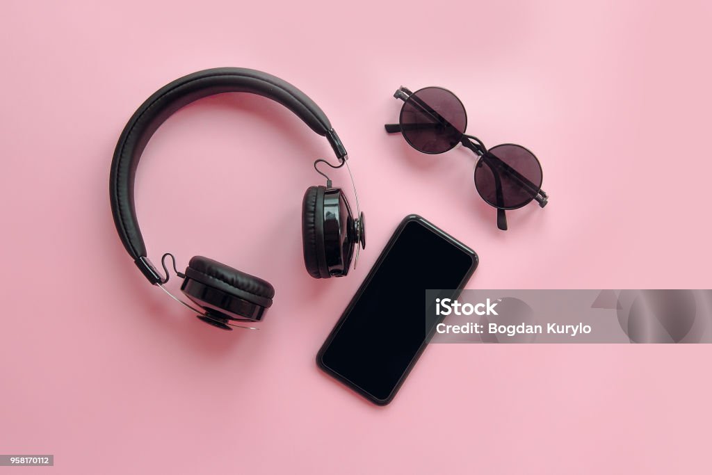 óculos de sol pretos elegantes, smartphone e fones de ouvido no fundo rosa, apartamento leigos. imagem moderna. itens pretos em papel rosa. Instagram blogging. espaço para texto. férias de verão - Foto de stock de Fone de Ouvido - Equipamento de som royalty-free