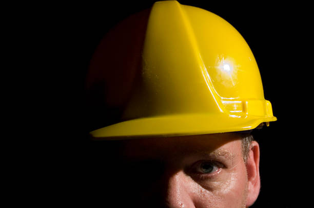 Hard hats hanging on hook against the dirty white wall.