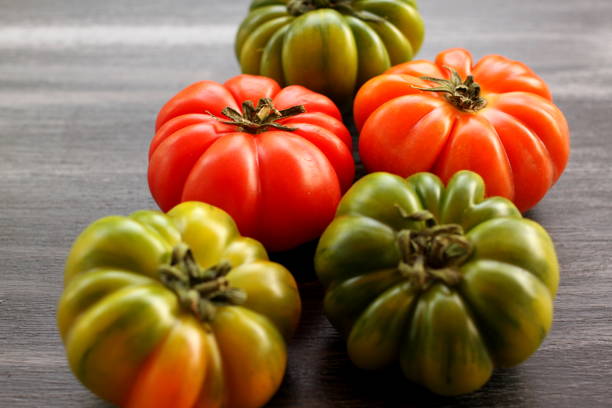 istock Red and green tomatoes on black table, closeup, high angle view 958183674