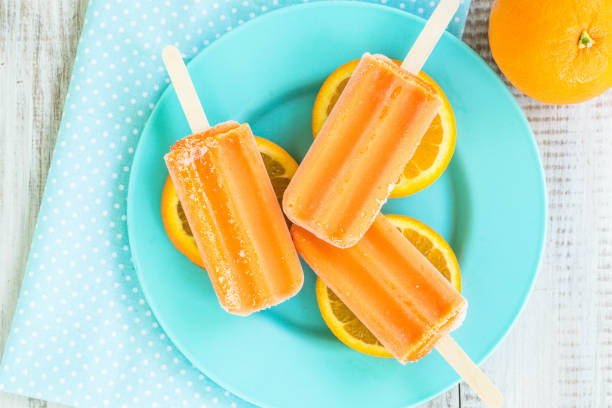 istock Orange Popsicles on Blue Dish Summer Dessert 958191948
