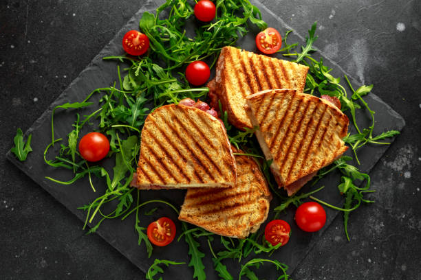 istock Grilled Bacon, cheese sandwich and served on stone platter with arugula and tomatoes 958213018