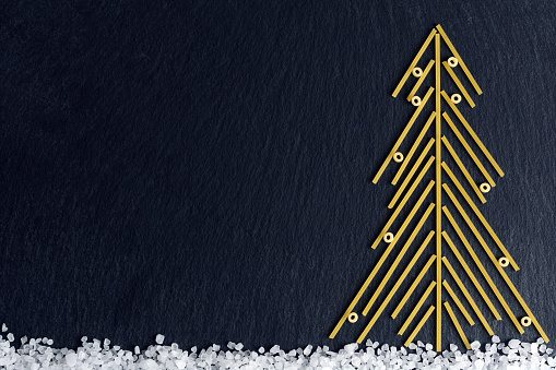 Christmas tree made with italian spaghetti with salt on a slate background.
