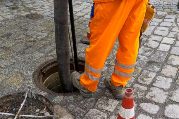 sewerage worker on street cleaning pipe