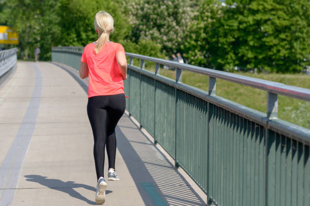 istock Blond woman jogging away from the camera 958228898