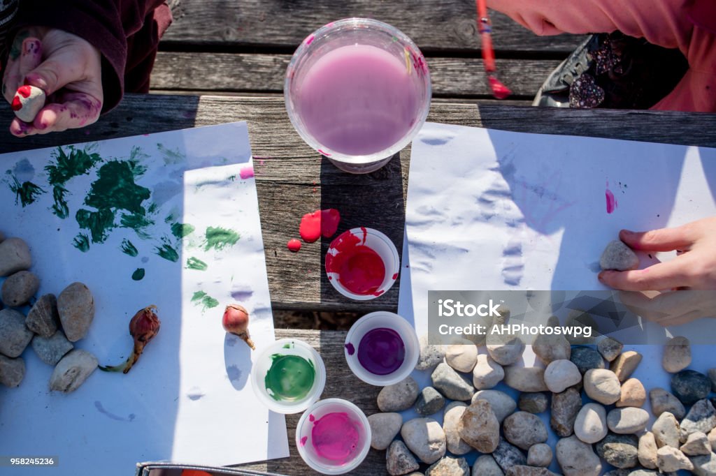 mixing paint Kids are painting rocks during craft time in the gardens Art Stock Photo