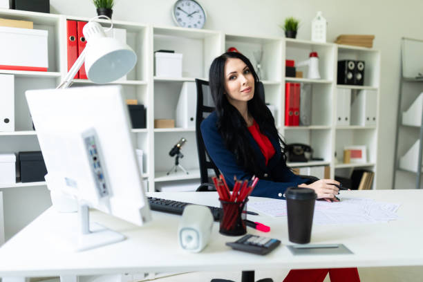 istock Beautiful young girl is looking through documents, sitting in the office at the table. 958260438