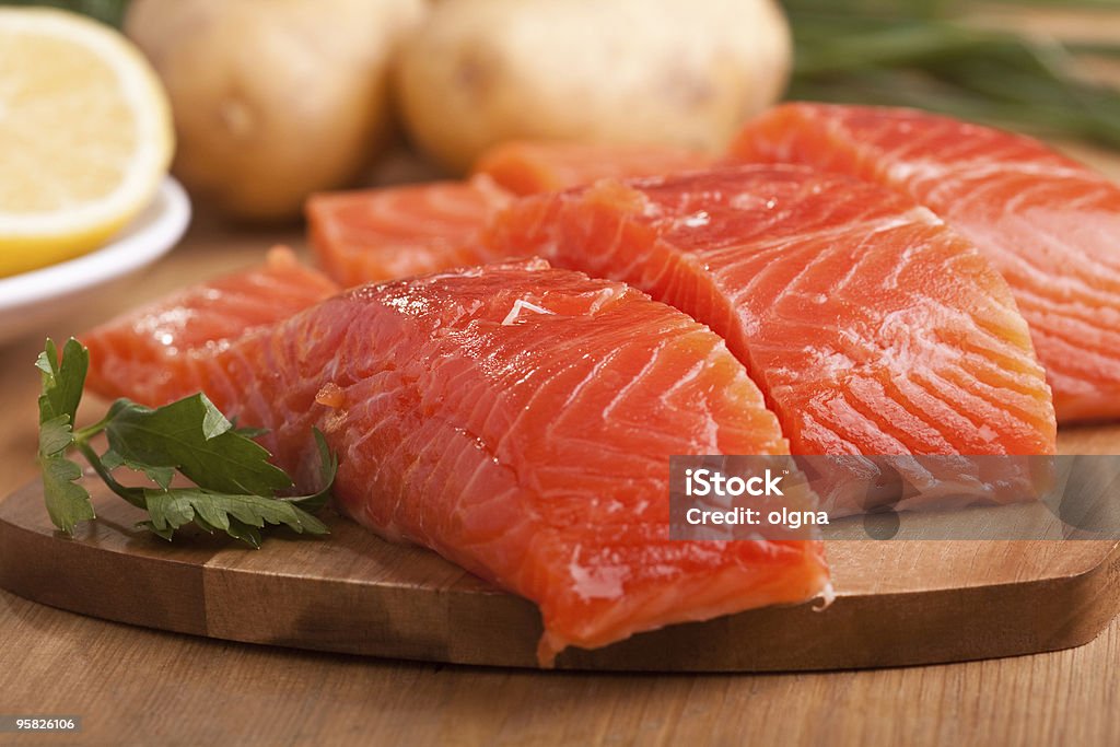 three salmon pieces on a chopping board three fresh salmon pieces with lemons on a chopping board Citrus Fruit Stock Photo