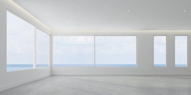 istock 3D rendering of white room space with interior lighting and sun light cast the window shadow on the wall and floor on sea view background,Perspective of minimal design architecture 958295772