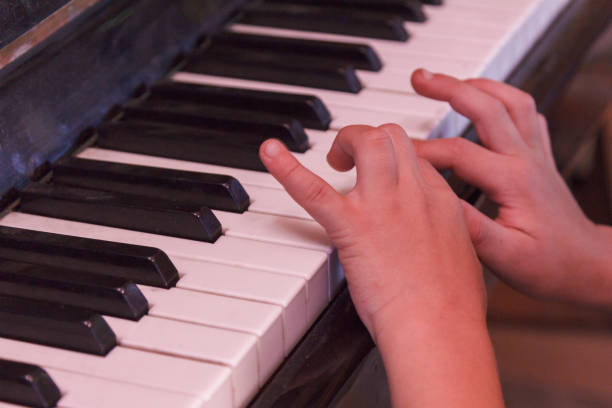 istock Child plays old piano with hands. 958317626