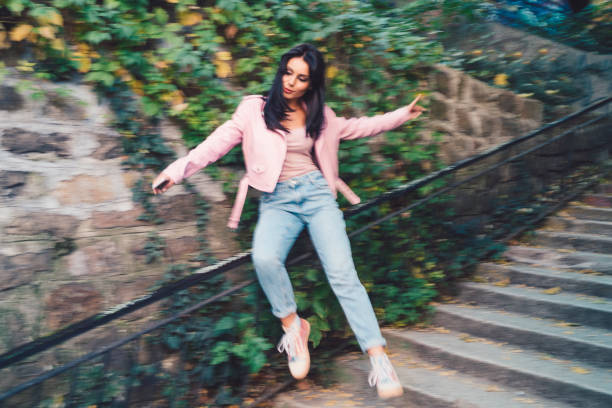 Joyful woman sliding down on the handrail Playful woman outside sliding down for fun sliding down stock pictures, royalty-free photos & images