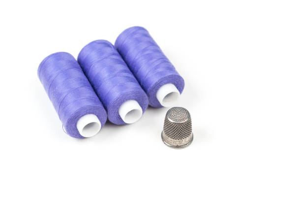 tres hilos de coser de color púrpura con el viejo dedal metal sobre un fondo blanco - thimble sewing item close up studio shot fotografías e imágenes de stock