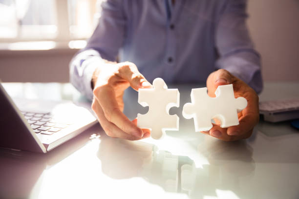 istock Businessperson's Hand Holding Two Jigsaw Puzzle 958335664