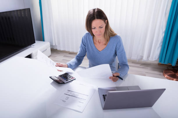 istock Woman Calculating Invoice With Calculator At Home 958336168