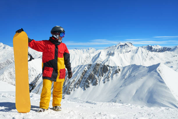 istock snowboarder standing with board high in the mountains i 958338862
