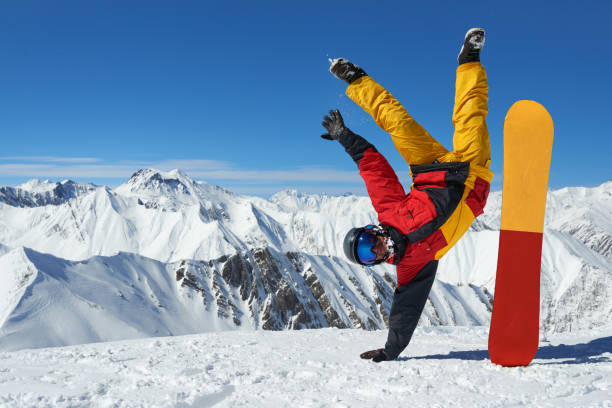 istock Man standing on hand upside down near snowboard 958339094