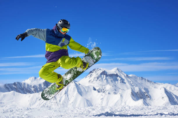 Snowboarder doing trick Snowboarder in bright sportswear doing trick against of beautiful mountains boarding photos stock pictures, royalty-free photos & images