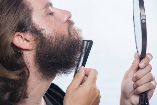istock Young man comb his beard and moustache isolated on white background 958340344