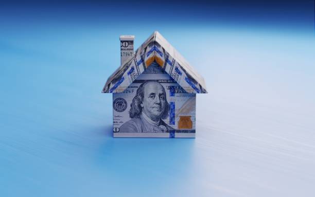 istock Tiny House Model Textured With One Hundred American Dollar Banknotes On Blue Wood Surface 958343320