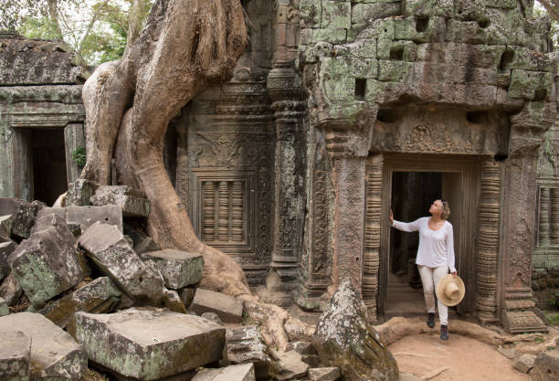 pausas de la mujer en la puerta de la antigua ruina, ta prohm - cambodia khmer architecture outdoors fotografías e imágenes de stock