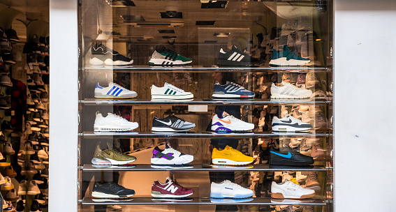 London, UK - 21 March, 2018: retail display of trendy sneakers displayed in the window of a shoe shop in central London, UK. The sneakers are displayed neatly in a row, and include brands such as Adidas, New Balance and Nike. Room for copy space.