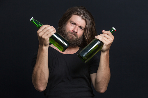 Bearded Man hipster holds bottle of beer isolated on black