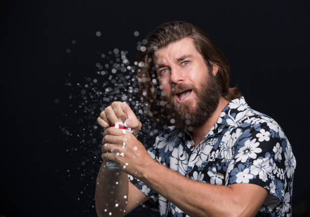 istock Man opens a bottle of cold beer spraying with splashes on black background 958345704