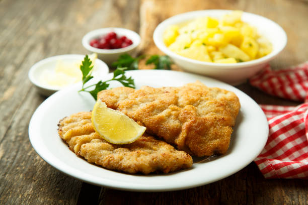 Homemade schnitzel with potato salad Schnitzel with potato salad, lemon and red berries schnitzel stock pictures, royalty-free photos & images
