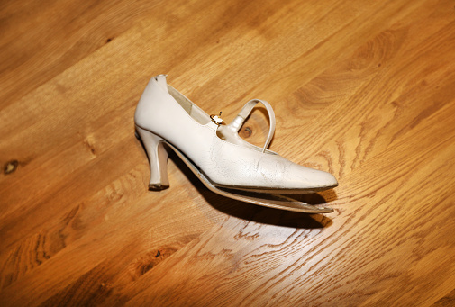 broken high heel white shoe on wooden background