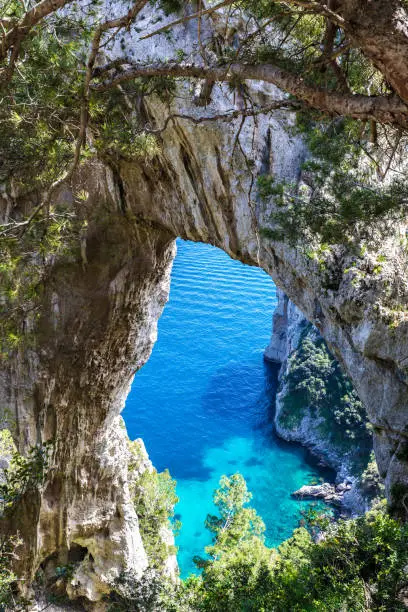 Photo of Capri Italy, island in a beautiful summer day, with faraglioni rocks and natural stone arch.