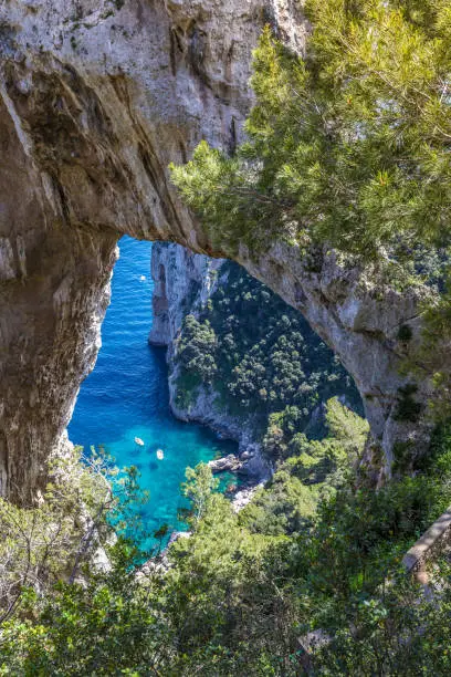 Photo of Capri, Italy. Capri Island in a beautiful summer day, with faraglioni rocks and natural stone arch. Beautiful blue water bay, seen by below the natural Arc.