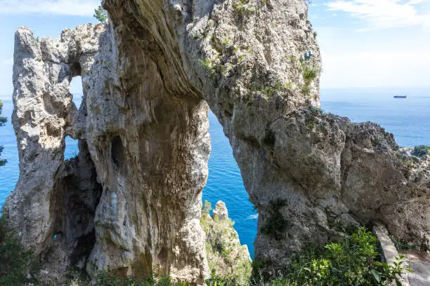 Photo of Capri, Italy. Capri Island in a beautiful summer day, with faraglioni rocks and natural stone arch. Beautiful blue water bay, seen by below the natural Arc.