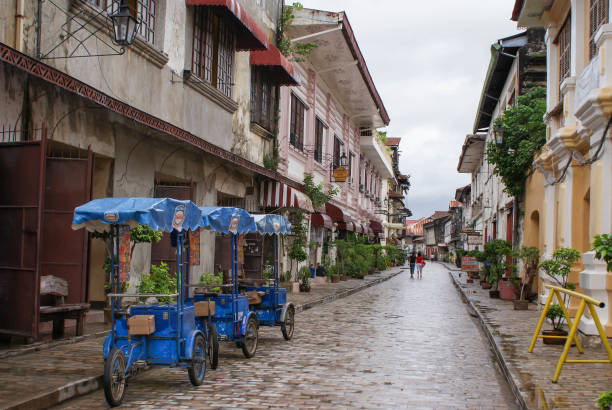 People and tricycles are seen in the beautiful colonial cobblestone streets of Vigan in North Luzon, Philippines. Unesco World Heritage Site Vigan, Philippines - June 17, 2009: People and tricycles are seen in the beautiful colonial cobblestone streets of Vigan in North Luzon, Philippines. Unesco World Heritage Site philippines tricycle stock pictures, royalty-free photos & images