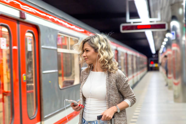 istock Young woman with suitcase looking at phone while waiting train in metro station. 958398604